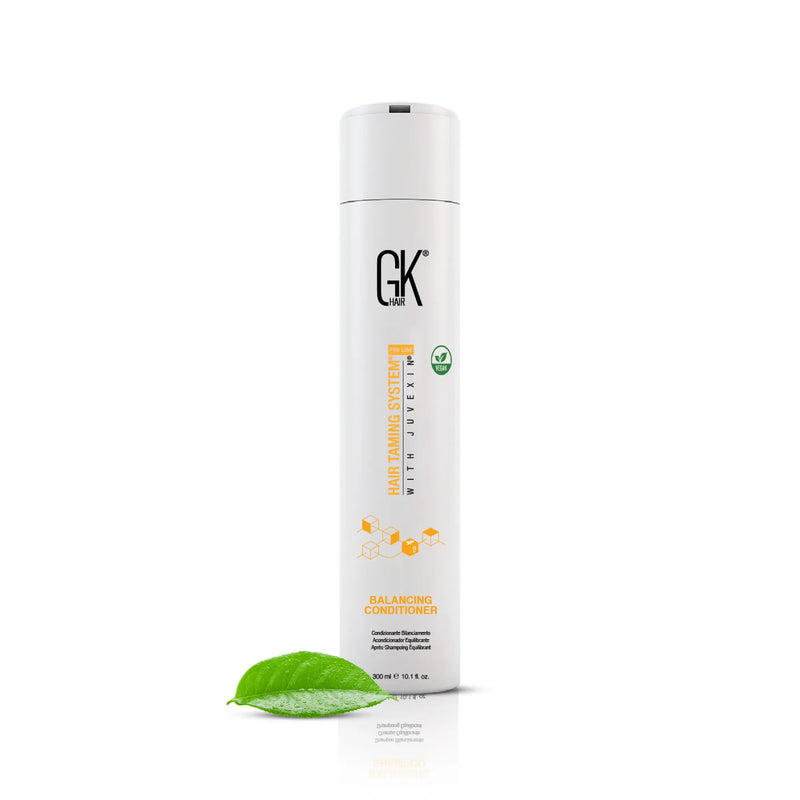 GK Hair Balancing Conditioner 300 ml white bottle standing beside a green tea leaf on a white background
