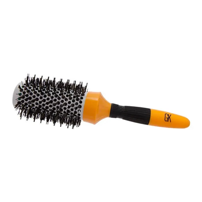 GK Hair Extra Round Brush lying on its side on white, side view of the vented barrel and orange non-slip handle