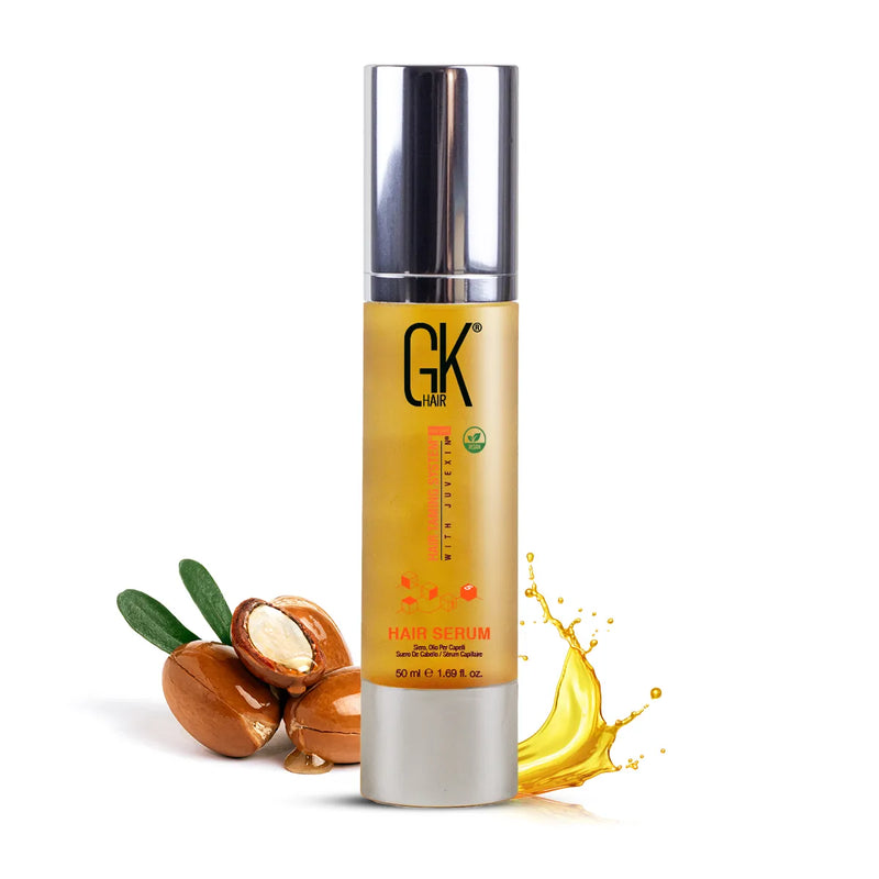 GK Hair Serum for Hair Pro 50 ml pump bottle flanked by cracked argan nuts and a golden oil splash