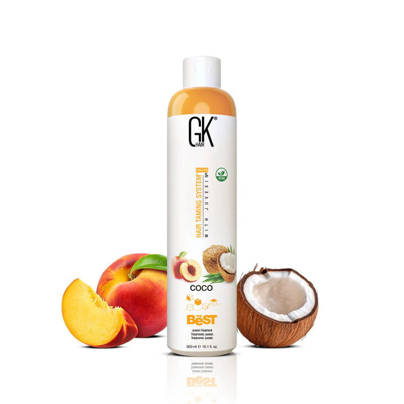 GK Hair The Best Vegan Hair Treatment Pro Coco 300 ml bottle between a sliced peach and a halved coconut