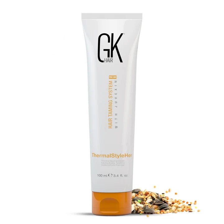 GK Hair ThermalStyleHer Hair Cream 100 ml white tube with orange cap, front view beside a scatter of seeds and grains